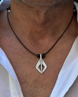 Silver pendant on a black cord necklace worn by a person in a white shirt.