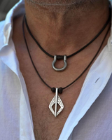 Close-up of a person wearing two necklaces with a white shirt background