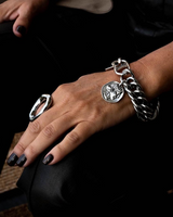 Close-up of a hand wearing a silver bracelet and ring on a dark background