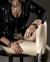 Funky silver-plated metal ring worn on the finger, featuring a hammered finish and adjustable fit, paired with leather pants.