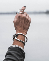 Hand with a silver bracelet and ring against a blurred background