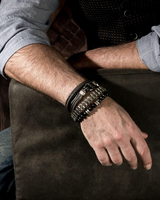Person wearing multiple bracelets on a wooden surface