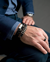 Close-up of a person's hands wearing multiple bracelets and a watch, with a focus on the jewelry.