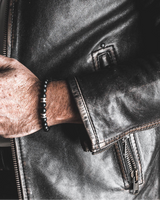 Close-up of a person wearing a black leather jacket with zippers.