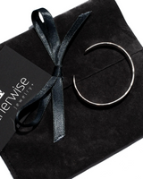 Silver-plated hammered bangle resting on a black suede pouch, featuring a sleek minimal design ideal for stacking.