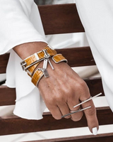 Yellow leather wrap bracelet with reptile pattern and bold silver buckle, worn with a matching cuff bangle.