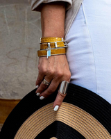 Yellow leather wrap bracelet stacked with a matching bangle, featuring reptile texture and bold metal accents.