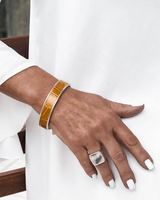 Bold yellow leather wrap bracelet paired with a silver bangle, worn on a model's wrist with stylish white nails.