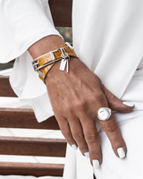 Striking yellow leather wrap bracelet with bold buckle, layered with a silver antique plated bangle, worn on a wrist.