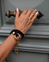 Hand with gold rings and bracelet on a gray door handle