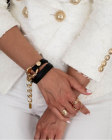 Close-up of a person wearing gold bracelets and rings on a white background