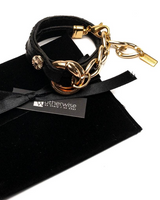 Black leather bracelet with gold chain on a black velvet pillow, branded 'Wutherwise'.