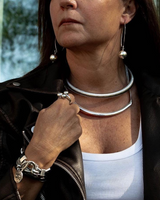Person wearing a black leather jacket, white top, and silver jewelry.