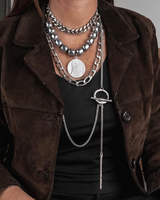 Three layered necklaces with stainless steel chains and dark semi-precious gemstone beads worn by a model in a black top.