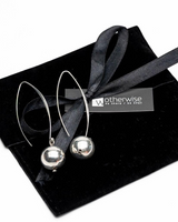 Silver earrings on a black ribbon with 'otherwise' branding on a black box.