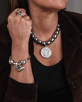 Layered stainless steel chain and gemstone necklace set worn by a model, featuring dark stones and shiny silver beads.