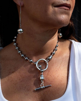 Close-up of a person wearing a silver necklace with a pendant.
