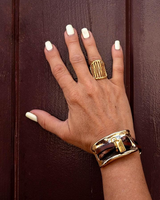 Hand with gold ring and bracelet on a brown background