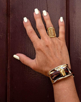 Hand with gold ring and bracelet on a brown background