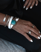 Close-up of a hand wearing multiple bracelets and rings on a dark background