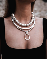 Layered silver ball chain choker set featuring a chunky ball chain and a hammered loop pendant, worn close to the collarbone.
