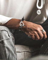 Person wearing a silver bracelet and ring, sitting on a checkered couch.