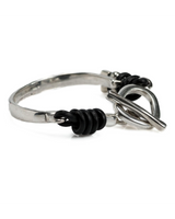 Silver ring with black cord and metal knot on a white background