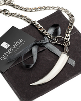 Silver necklace with a large pendant on a black box, branded 'otherwise jewelry'.