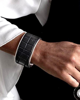 Person wearing a black leather cuff and holding a stethoscope against a dark background