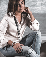 Woman sitting on a couch wearing a white shirt and jeans, with a blurred background.