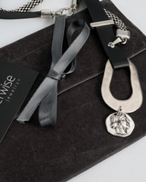 Silver necklace with pendant on a gray surface, featuring the 'otherwise jewelry' brand.