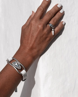 Silver lava leather set worn on a hand, showcasing a chunky bracelet with a crystal and white accents, alongside a silver ring.