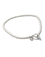 Chunky white lava stone choker with a silver T-clasp and a heart-shaped crystal charm, adjustable fit.