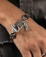 Silver bracelet with charms on a wrist against a dark background