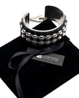 Black cuff bracelet with silver beads on a black velvet pillow, branded 'Wotherwise'.