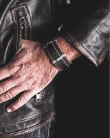 Hand wearing a watch on a leather jacket background