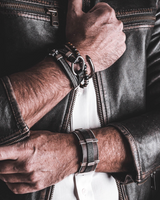 Person wearing a leather jacket with visible jewelry, including bracelets and a ring.