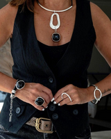 Chunky black resin necklace featuring a bold pendant and silver-plated Zamak metal accents, styled with a black vest.