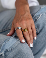 Hand with multiple rings on a denim background
