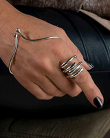 Hand wearing a silver bracelet and rings on a dark background