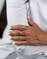 Close-up of a hand wearing multiple rings with a blurred background