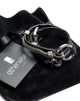 Black leather bracelet with silver clasp on a black velvet surface with 'otherwise' brand card.