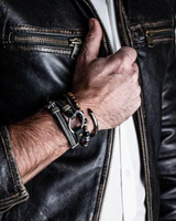Person wearing a black leather jacket with a close-up of their hand and jewelry.