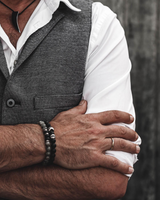 Man wearing a gray vest over a white shirt with a blurred background