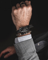 Person wearing multiple bracelets on a dark background