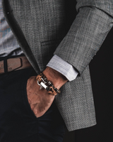 Person wearing a gray suit with a close-up of a bracelet on a dark background