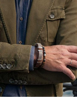 Person wearing a brown jacket with a focus on the arm and wrist, showing a bracelet.