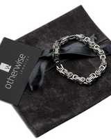Silver chain bracelet on a dark fabric with 'otherwise jewelry' card