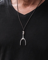 Person wearing a black shirt with a necklace featuring a unique pendant.