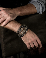 Person wearing multiple bracelets on a dark background